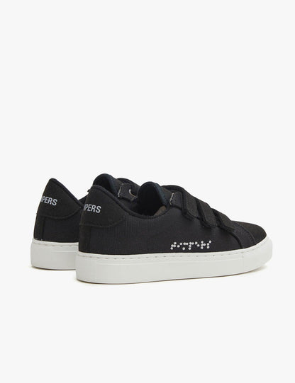 Kids Black. Zapatilla de lona negra con 3 tiras de velcro negras. Suela blanca, braille blanco. 