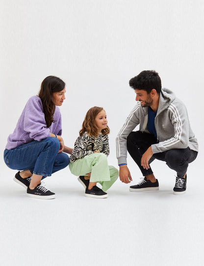 Kids Black. Zapatilla de lona negra con 3 tiras de velcro negras. Suela blanca, braille blanco. 